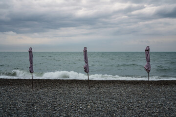 A deserted beach with umbrellas on the Sochi coast against the background of the Black Sea, Adler,...