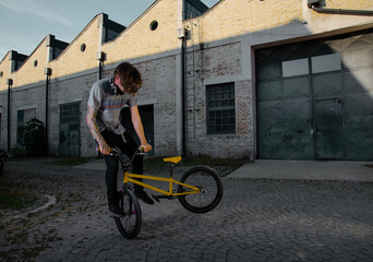 Hipster tattooed man, with extreme bike posing outdoors  