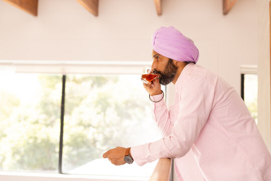 Drinking tea, Indian man in turban relaxing at home, looking out window, copy space - Powered by Adobe