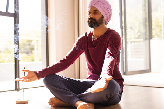 Meditating at home, Indian man sitting cross-legged with incense burning