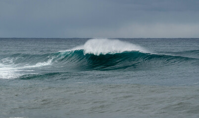 Fototapeta premium Large blue wave breaking out at sea, wild ocean