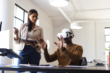 Using VR headset, man interacting with virtual environment while woman holds tablet