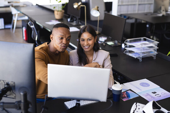 Collaborating at office desk, colleagues discussing project on computer screen