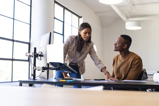Business colleagues discussing project, using laptop and documents in modern office