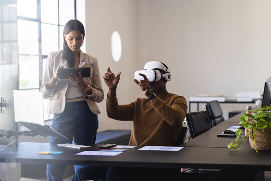 Using VR headset, man interacting with virtual environment while woman taking notes