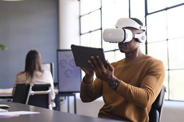 Using VR headset and holding tablet, man working in modern office setting