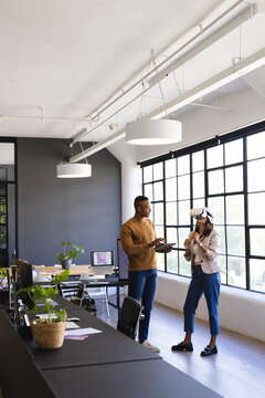 Discussing project, colleagues using VR headset and tablet in modern office, copy space