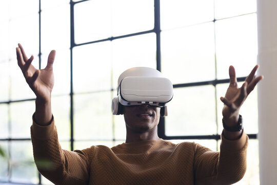 Using VR headset, man experiencing virtual reality in modern office setting, copy space