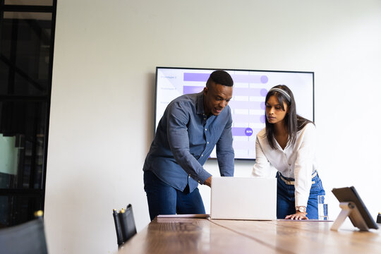 Collaborating on project, colleagues discussing data using laptop in office meeting
