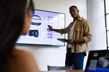 Presenting VR headset data, man using tablet in business meeting with colleagues