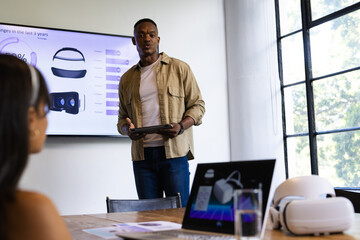 Presenting data, man holding tablet and explaining VR headset statistics in meeting