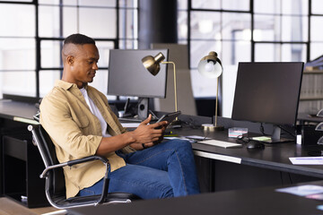 Using tablet, man sitting at desk in modern office, working efficiently