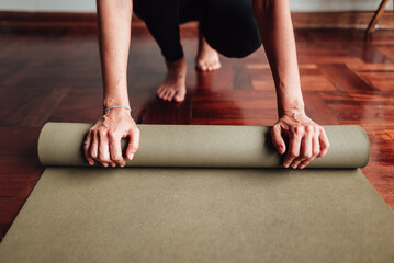 Hands of a woman rolling up a yoga mat. Copy Space