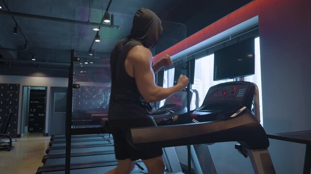 Sporty Boxer Man in 30s Trains Shadowboxing Technique and Boxing Combinations While Walking on Treadmill in Empty Modern Gym with Changing Ambient Light