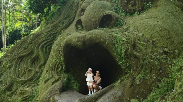 Female Tourist And Daughter Posing At Mouth Cave In Alas Harum Bali, Tegallalang, Indonesia. panning, slow motion