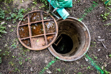 New home construction site, old sewar system entrance with rusty iron lid off and building site...