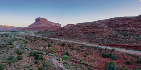 Red cliff, shrubs, butte and mesa rock formations in the desert at sunrise. Moab, Utah, United States of America.