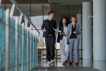 Diverse group businesspeople walking to meeting at modern office. Businessmen and businesswoman chatting talk with tablet and document paper. Manager orders work on way to office.