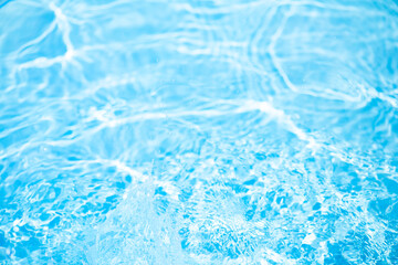 Blue water with ripples on the surface. Defocus blurred transparent blue colored clear calm water surface texture with splashes and bubbles. Water waves with shining pattern texture background.