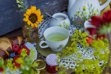 Morning summer tea with flowers and fruits on the veranda in the village house