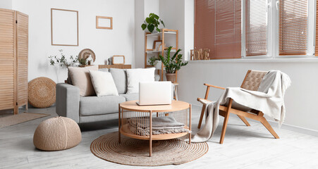 Interior of modern living room with grey sofa and laptop on wooden coffee table