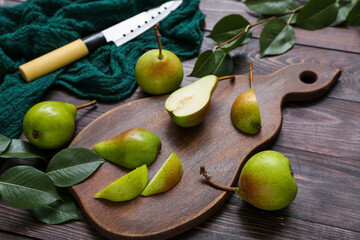 Board with sliced pears and knife on dark wooden table