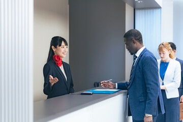 ホテルのフロントで手続きする多国籍の人々