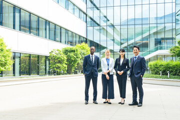 オフィスビルの前に並ぶ多国籍ビジネスパーソンのグループ