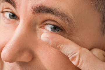 Mature man putting in contact lenses, closeup