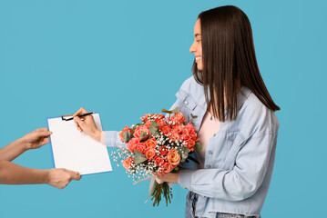 Young woman receiving bouquet of beautiful flowers on blue background