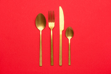 Golden cutlery on red background