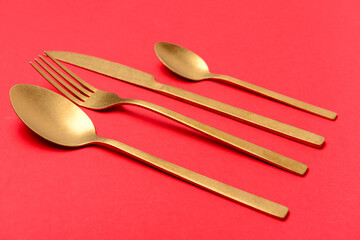 Golden cutlery on red background