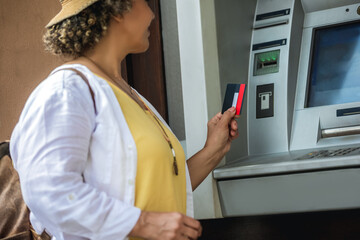 Female African American tourist standing at the ATM machine getting ready to enter the pin.