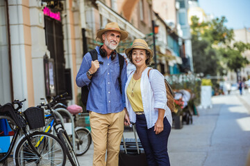 Fototapeta premium Elderly married couple walking through the new city with backpacks.