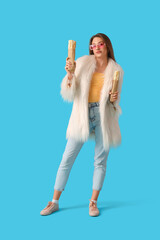 Stylish young woman with doner kebabs on blue background