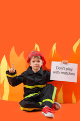 Cute little firefighter holding paper with text DON'T PLAY WITH MATCHES and flame on orange background