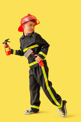 Cute little firefighter with toy tools running on yellow background