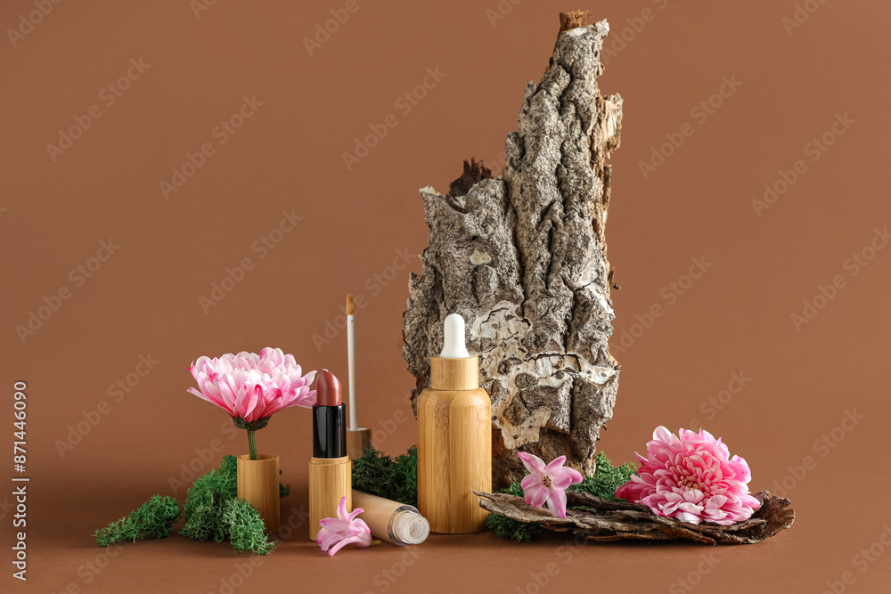 Wall mural Concealer, green moss, flowers, lipstick, bottle of serum and tree bark on brown background