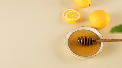 Honey with fresh lemons and fresh mint leaves on beige. Copy space