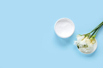 Jar of cream and beautiful freesia flowers on color background