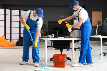 Male workers of cleaning service disinfecting in office
