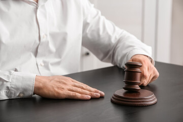 Male lawyer with judge gavel sitting by table in office, closeup