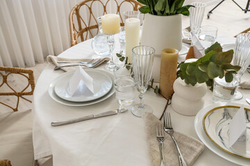 Beautiful table setting with eucalyptus and candles for wedding celebration in room, closeup