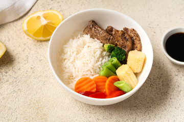 Bowl of tasty rice with chicken and vegetables on light background