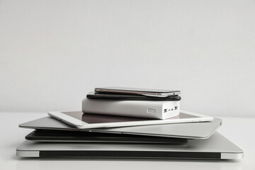 Stack of different modern gadgets on light background