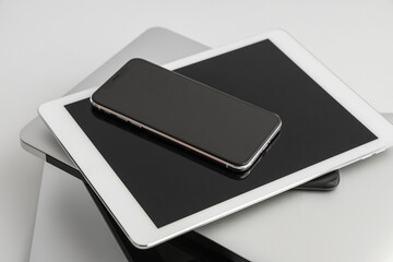 Stack of different modern gadgets on light background, closeup