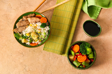 Composition with bowls of tasty rice, vegetables and soy sauce on color background