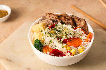 Bowl of tasty rice with chicken and vegetables on color table