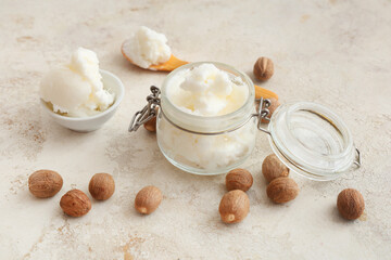 Glass jar with shea butter and nuts on grunge background