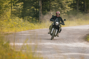 Obraz premium Modern adventure motorcycle on a ride on gravel surface. Motorcycling in nature or offroad, enjoying freedom. Motorbike in the woods. Making a turn